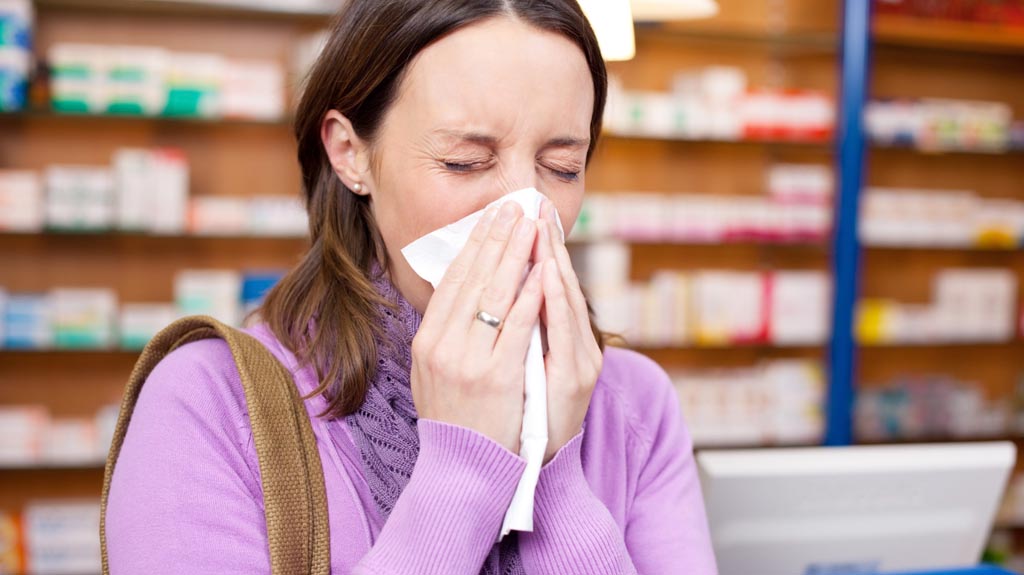 Woman sneezing into a tissue due to allergies